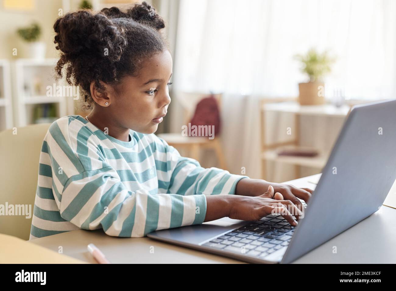 Side view portrait of cute black little girl using laptop while