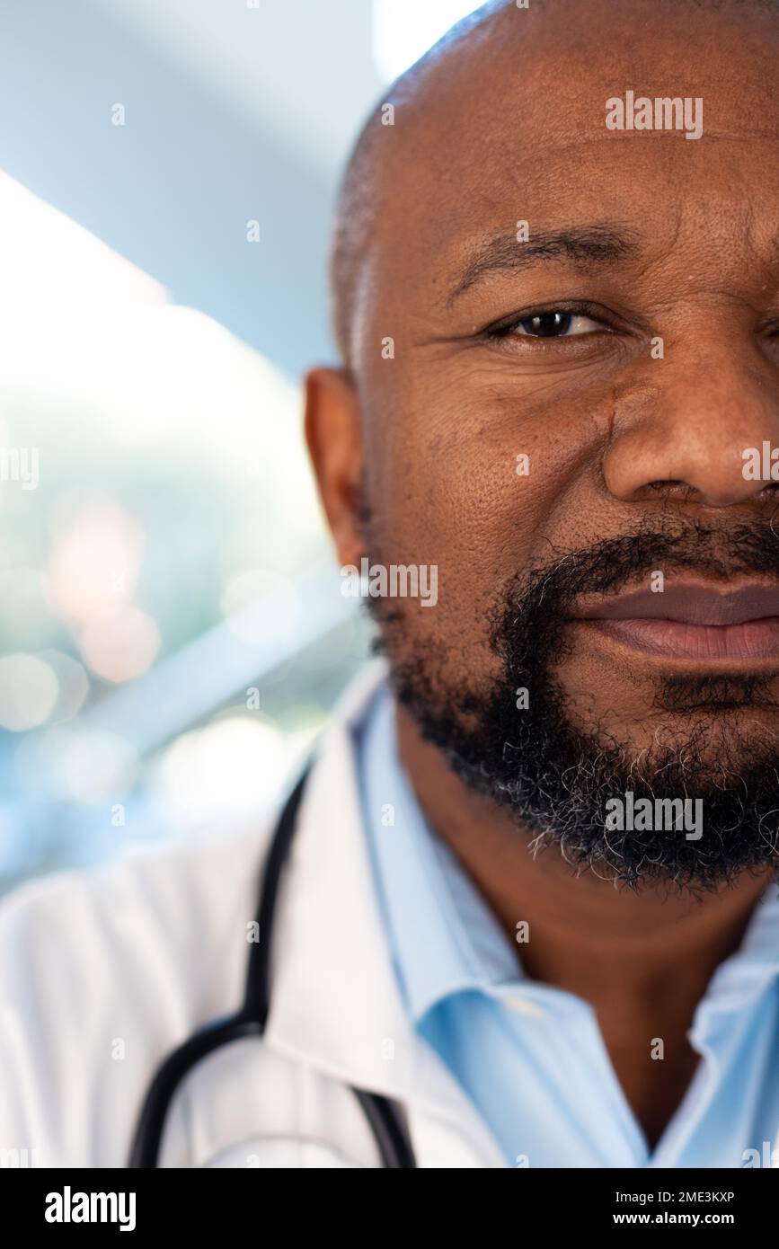 Vertical half face portrait of smiling african american male doctor in hospital corridor Stock Photo
