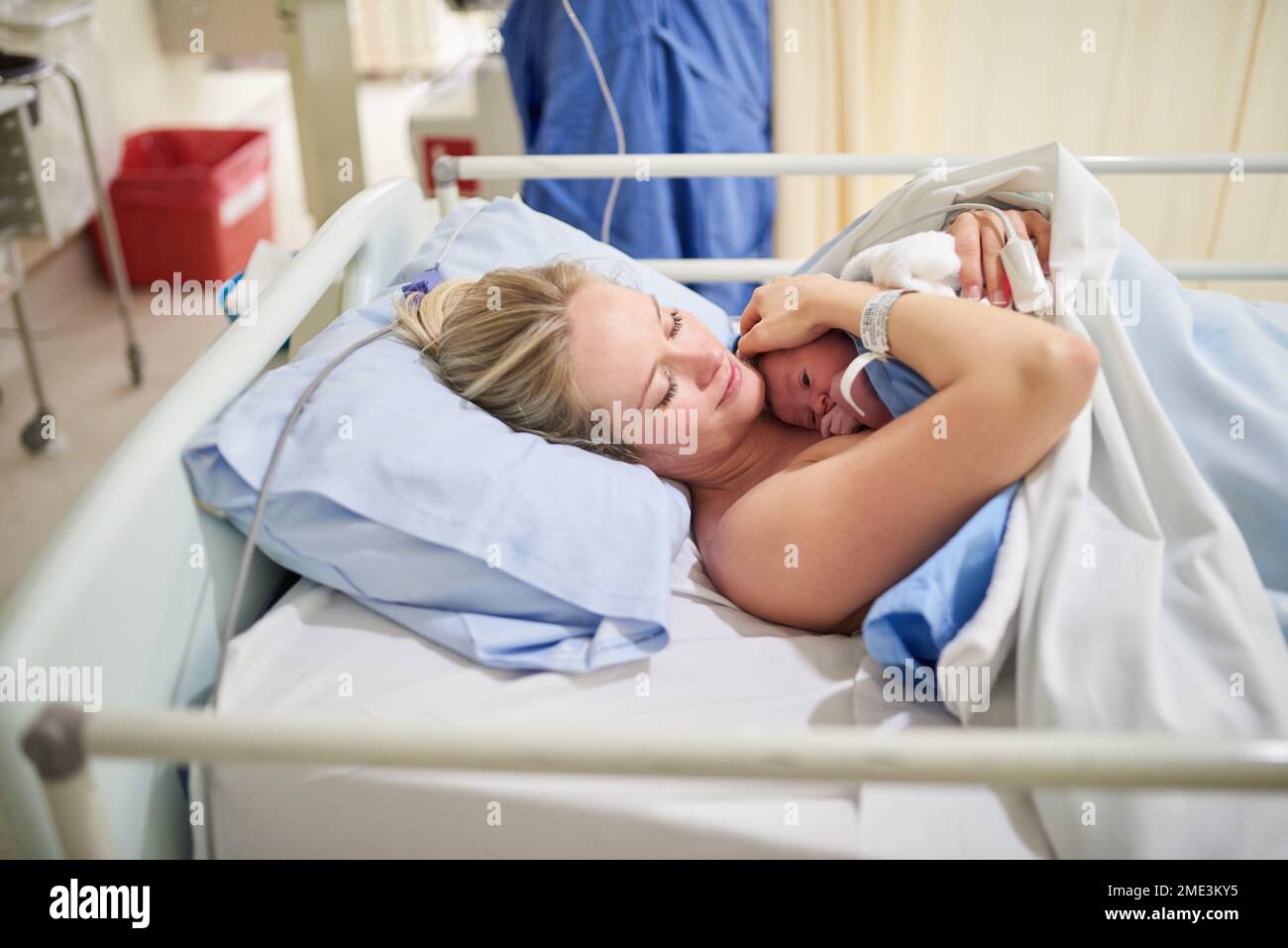 Ill hold you dear to me forever. a beautiful young mother lying in bed with her newly born baby girl in the hospital. Stock Photo