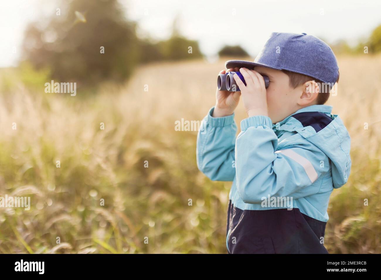 Boy looking through binoculars on field Stock Photo