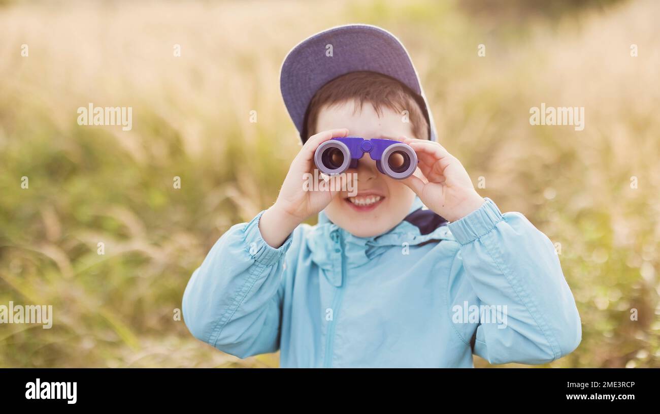 Happy boy looking through binoculars on field Stock Photo