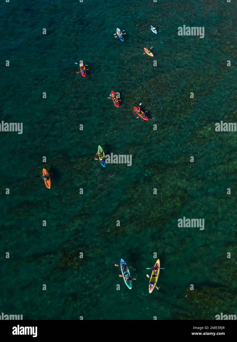 Group of people kayaking in the sea near a white rocky coastline.People active, healthy lifestyle Stock Photo