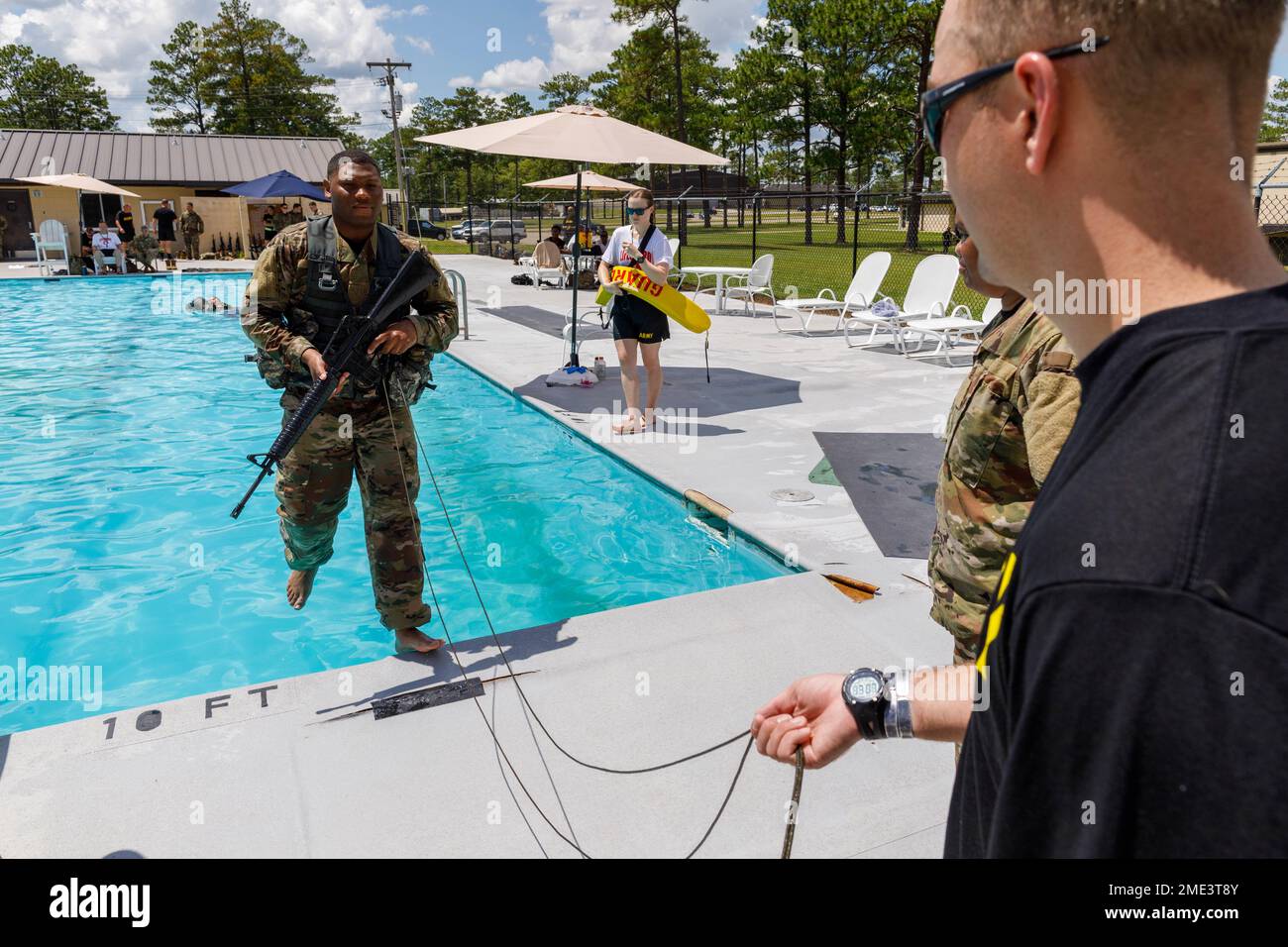 Army Reserve Capt. Christopher Carroll, human resource officer for the 160th Military Police Battalion, jumps into a pool as, 1st Lt. Thomas Harvey, executive officer for the 308th Military police company, 535th MP Battalion, holds a cord tied to Capt. Carroll’s rifle during water survival training, July 27, 2022, at Camp Shelby Joint Forces Training Center, Mississippi. After entering the water, Capt. Carroll removed his gear and swam to the end of the pool while 1st Lt. Harvey pulled the rifle from the water. (Arizona Army National Guard photo by Sgt. 1st Class Brian A. Barbour) Stock Photo