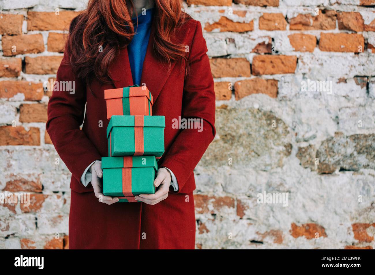 Woman holding gifts standing in front of wall Stock Photo