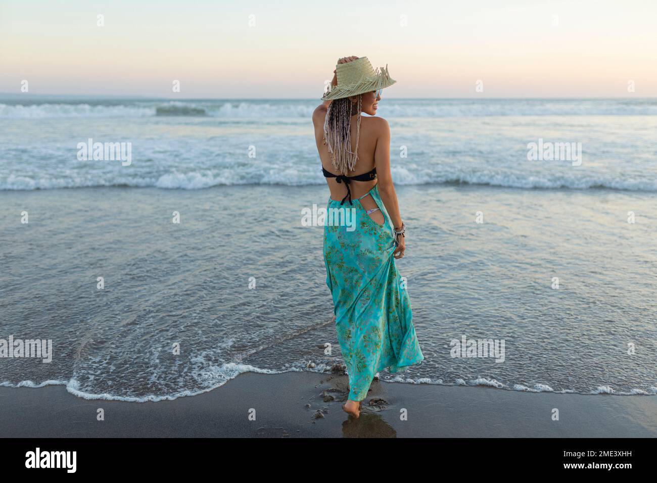Young woman with hat standing in front of sea at beach Stock Photo - Alamy