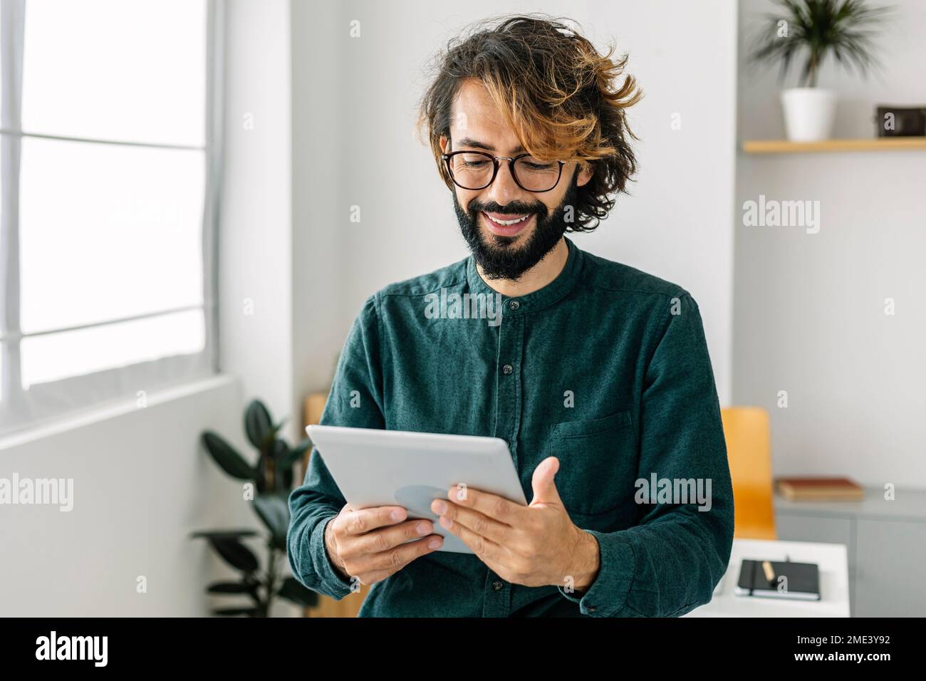 Happy freelancer using tablet PC in office Stock Photo