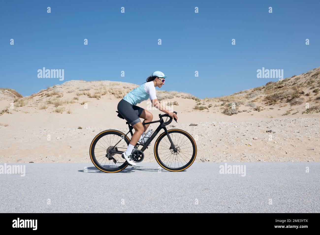 Mature cyclist riding bicycle on road by sand dunes Stock Photo