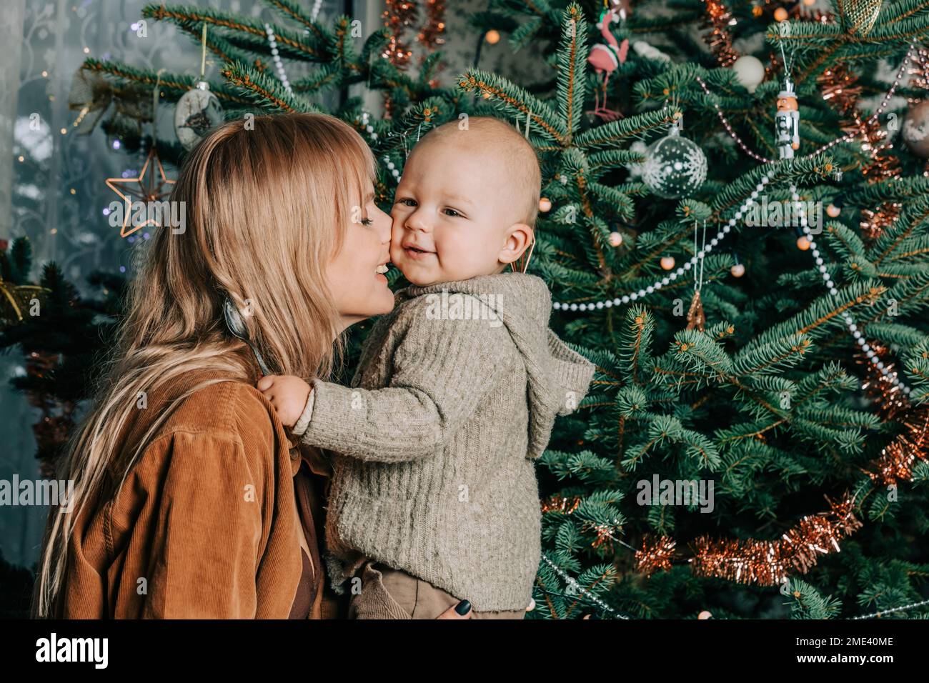 Happy mother embracing baby boy in front of Christmas tree Stock Photo