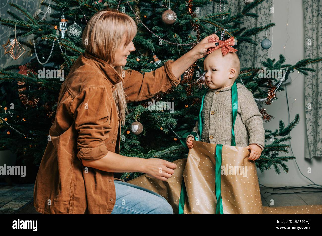 Happy mother playing with son standing in front of Christmas tree Stock Photo