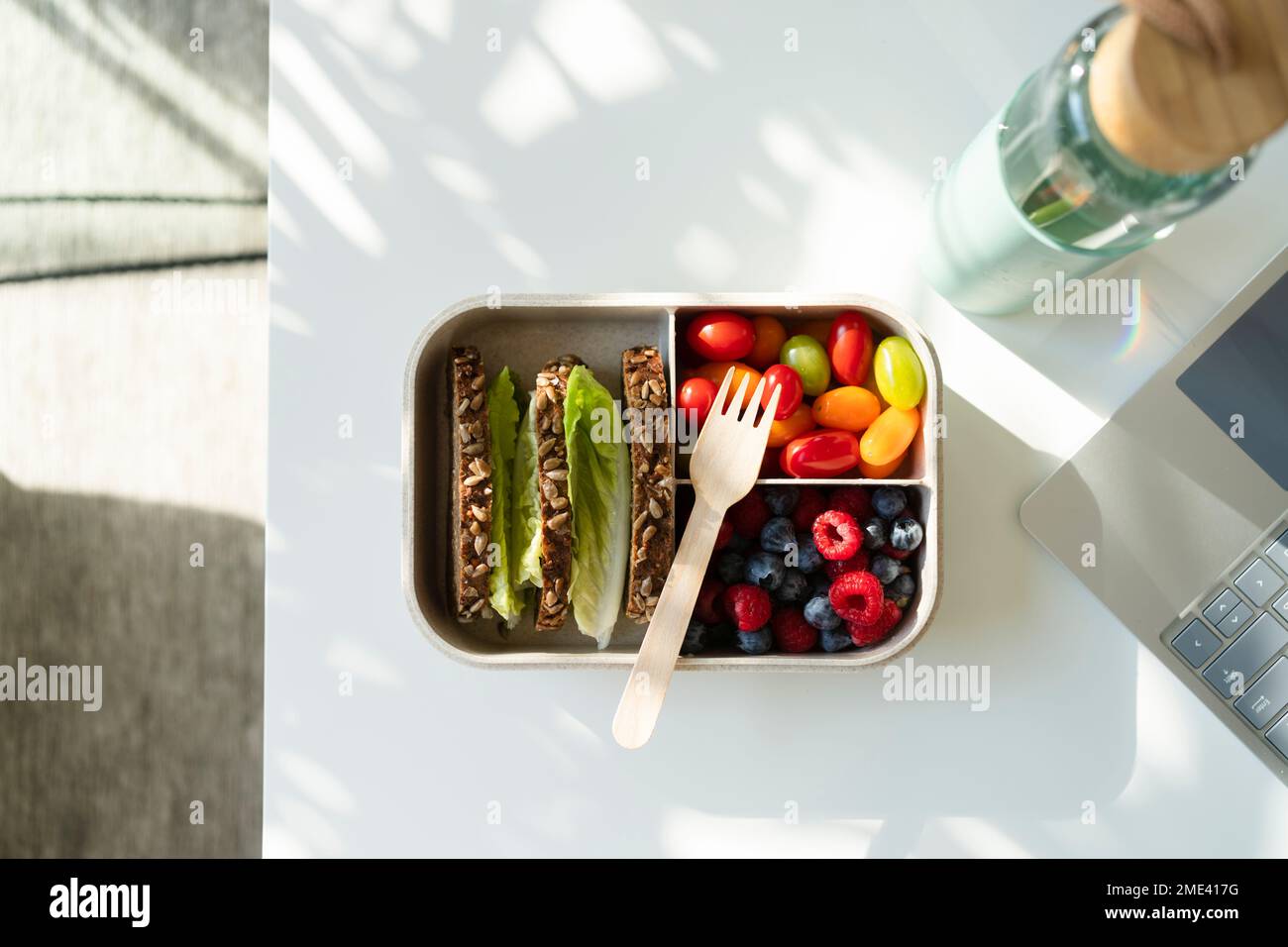 Rye bread, berries and salad with disposable fork in lunch box on table Stock Photo