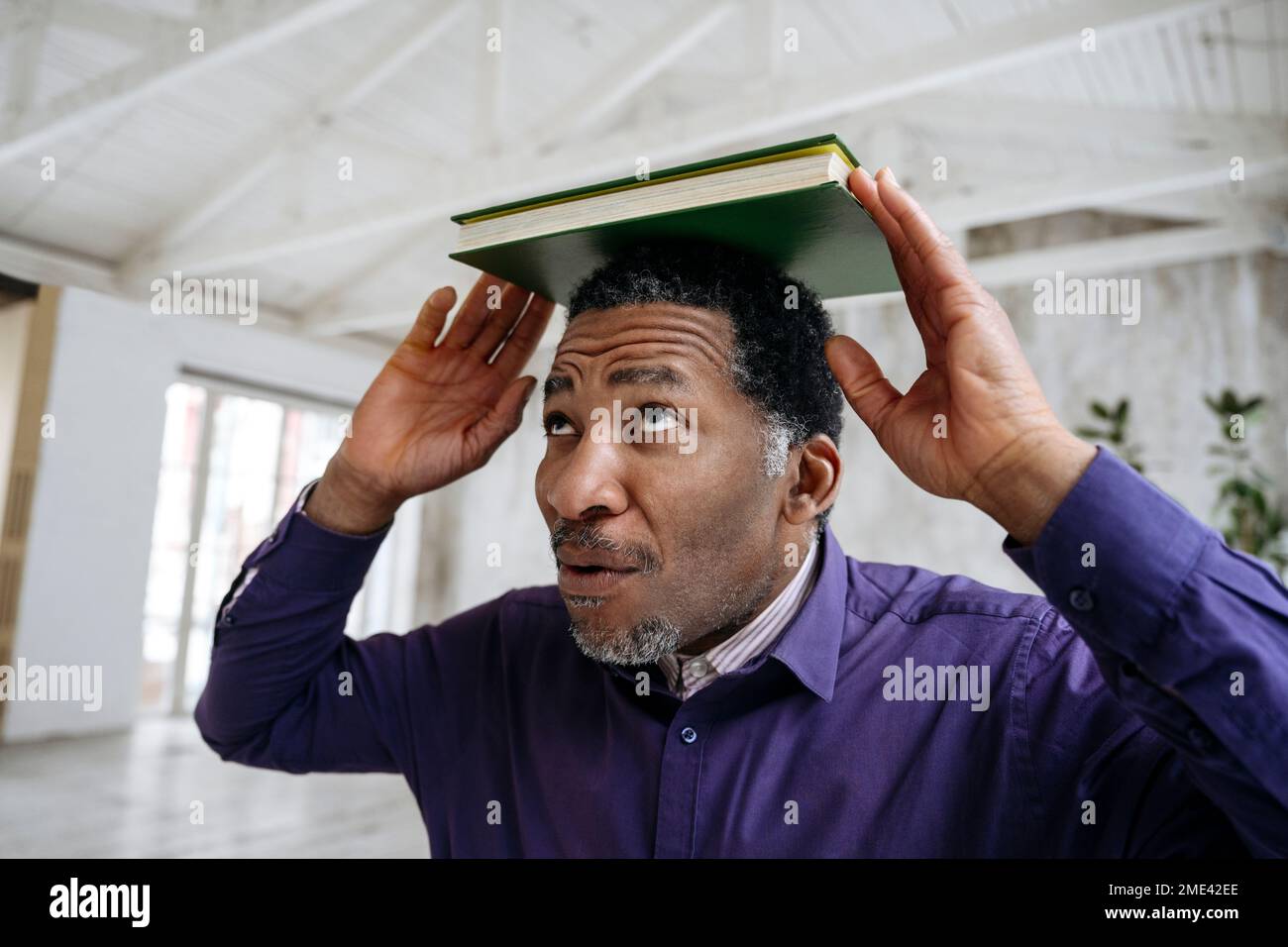Mature man balancing book on head Stock Photo Alamy
