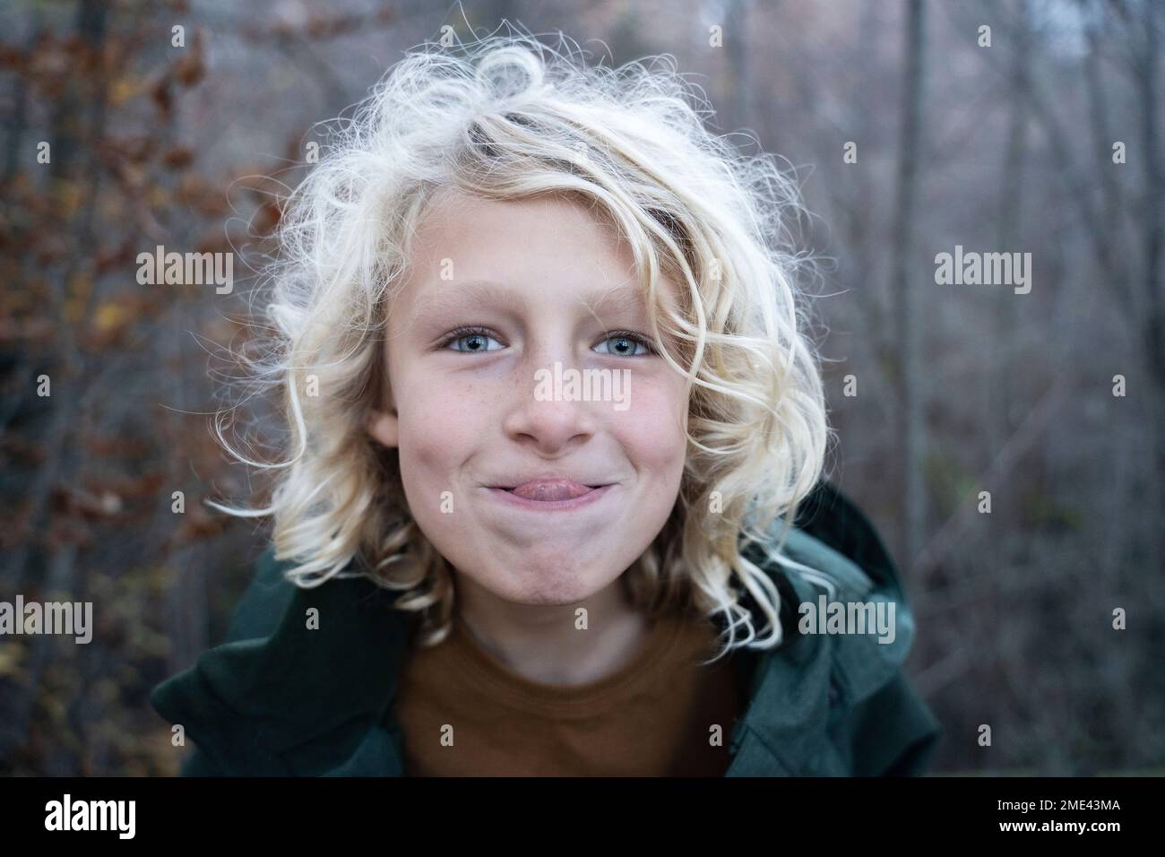 Boy with blond curly hair sticking out tongue Stock Photo - Alamy