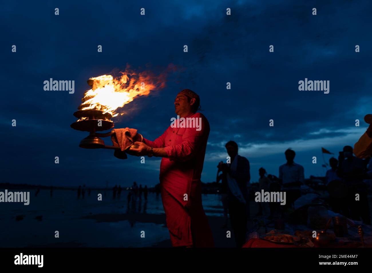 A Hindu priests rotate traditional oil lamps in circular movements as