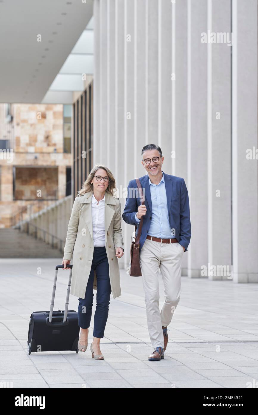 Business people walking with luggage on footpath Stock Photo
