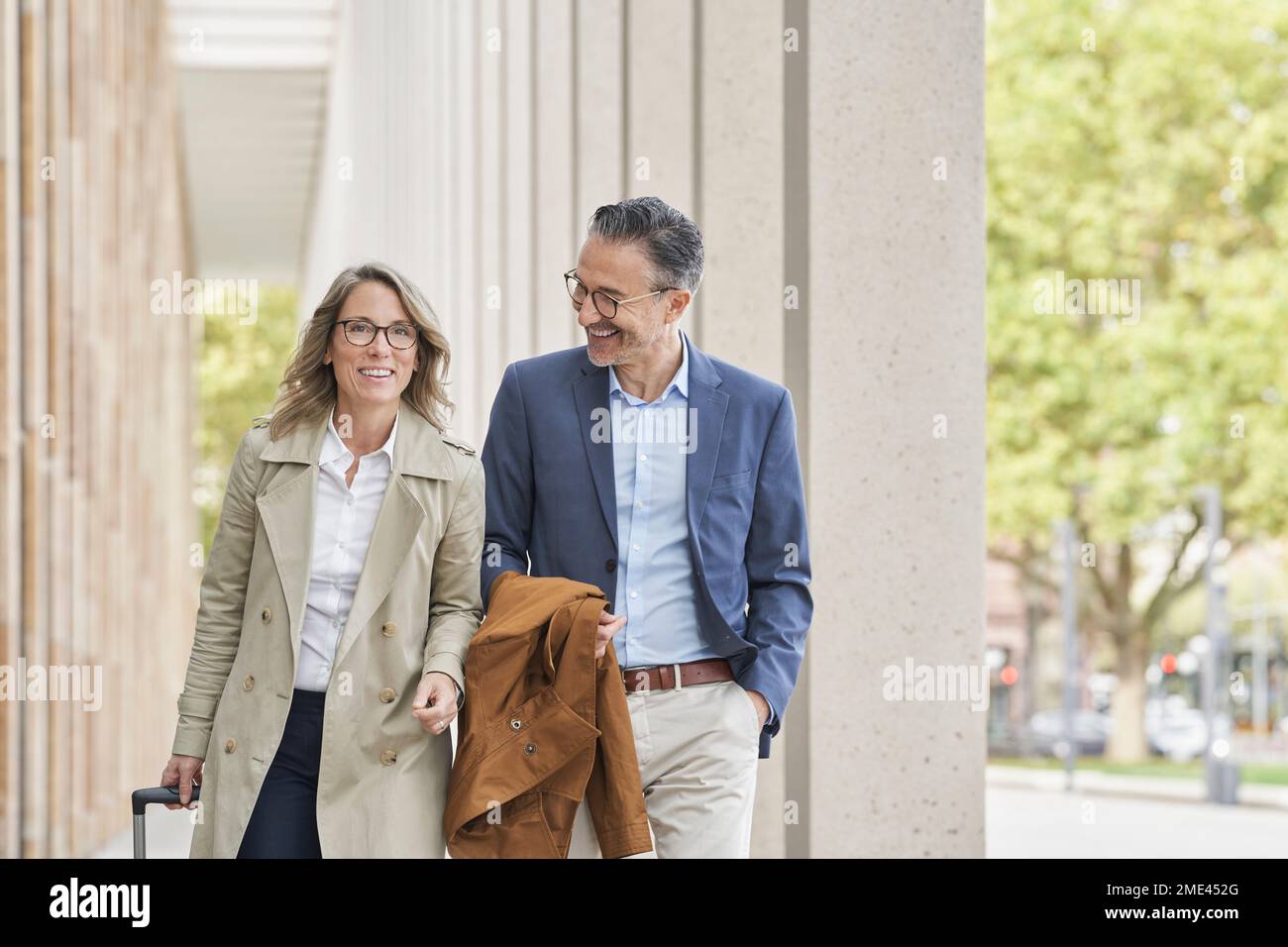 Happy business people walking together on footpath Stock Photo