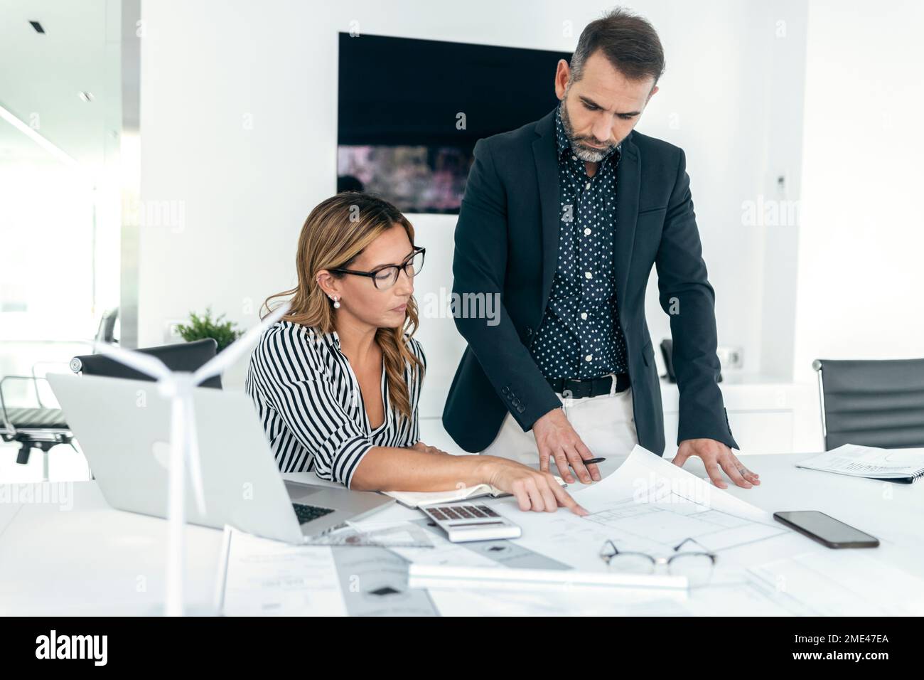 Architect explaining coworker over blueprint in office Stock Photo