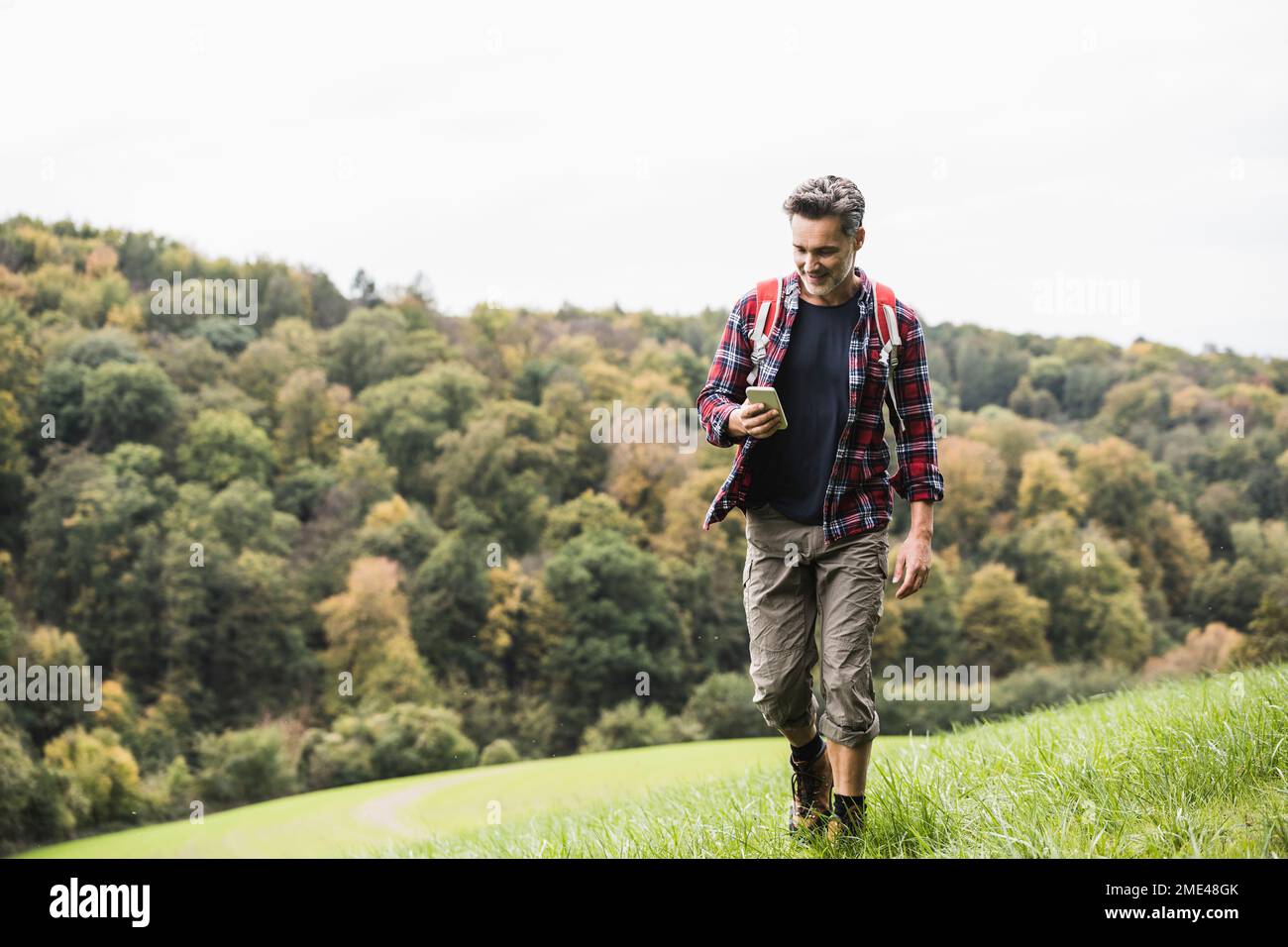 Mature man using smart phone walking on grass Stock Photo