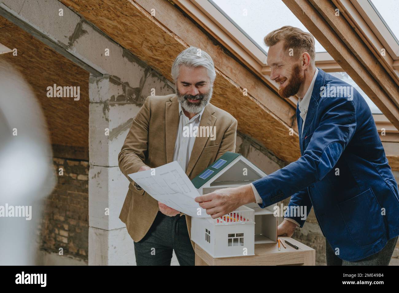 Smiling architects discussing over blueprints at construction site Stock Photo