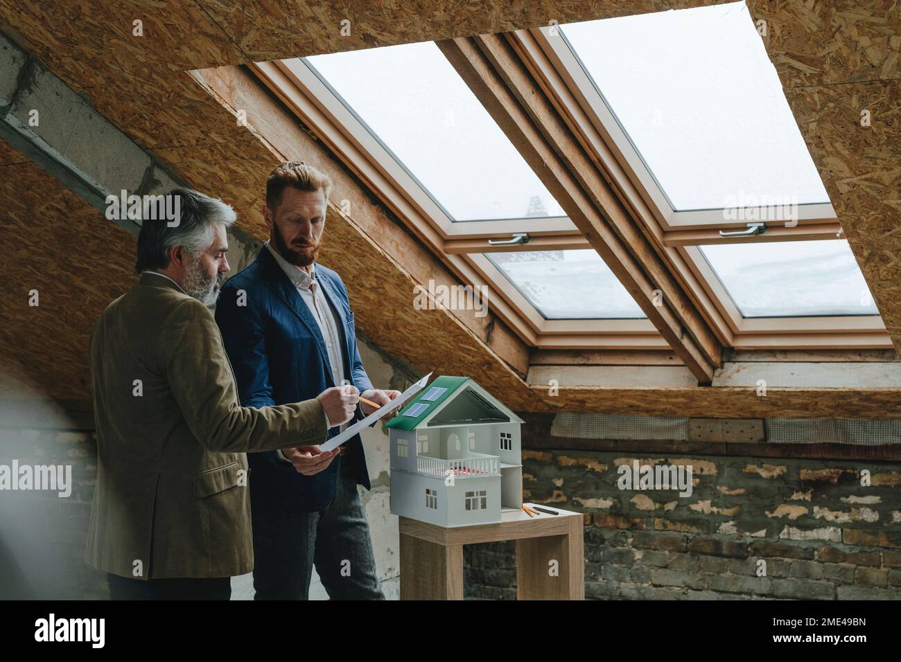 Architect pointing over blueprint and explaining colleague at construction site Stock Photo