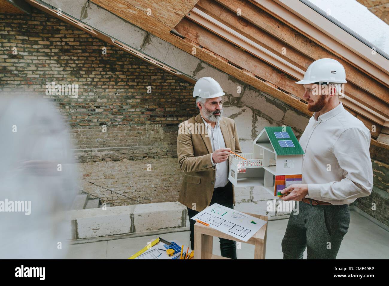 Architect explaining colleague standing with house model at ...