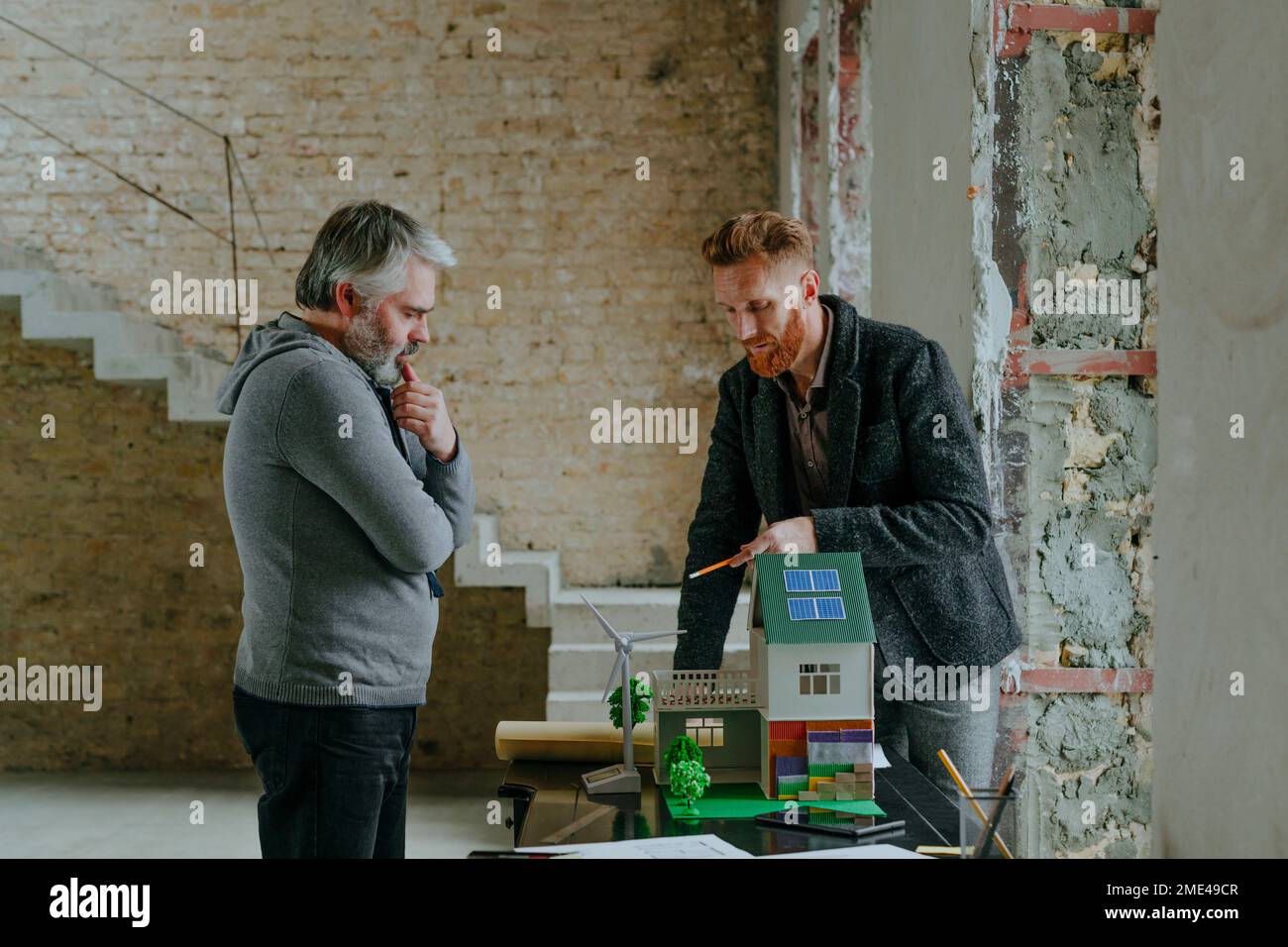 Architect explaining model house to customer at construction site Stock ...