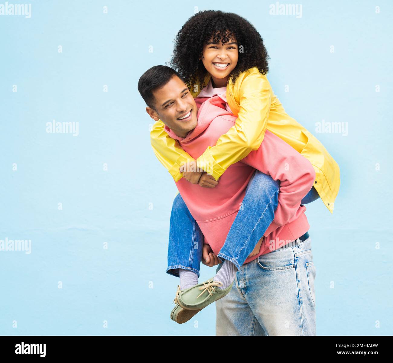 Happy couple, bonding or piggyback on isolated blue background in city travel, date or fun game. Smile, happy or man carrying black woman in silly Stock Photo