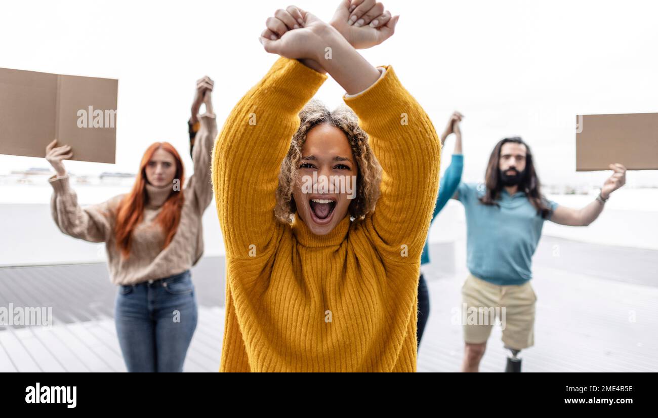Young woman protesting with arms raised Stock Photo