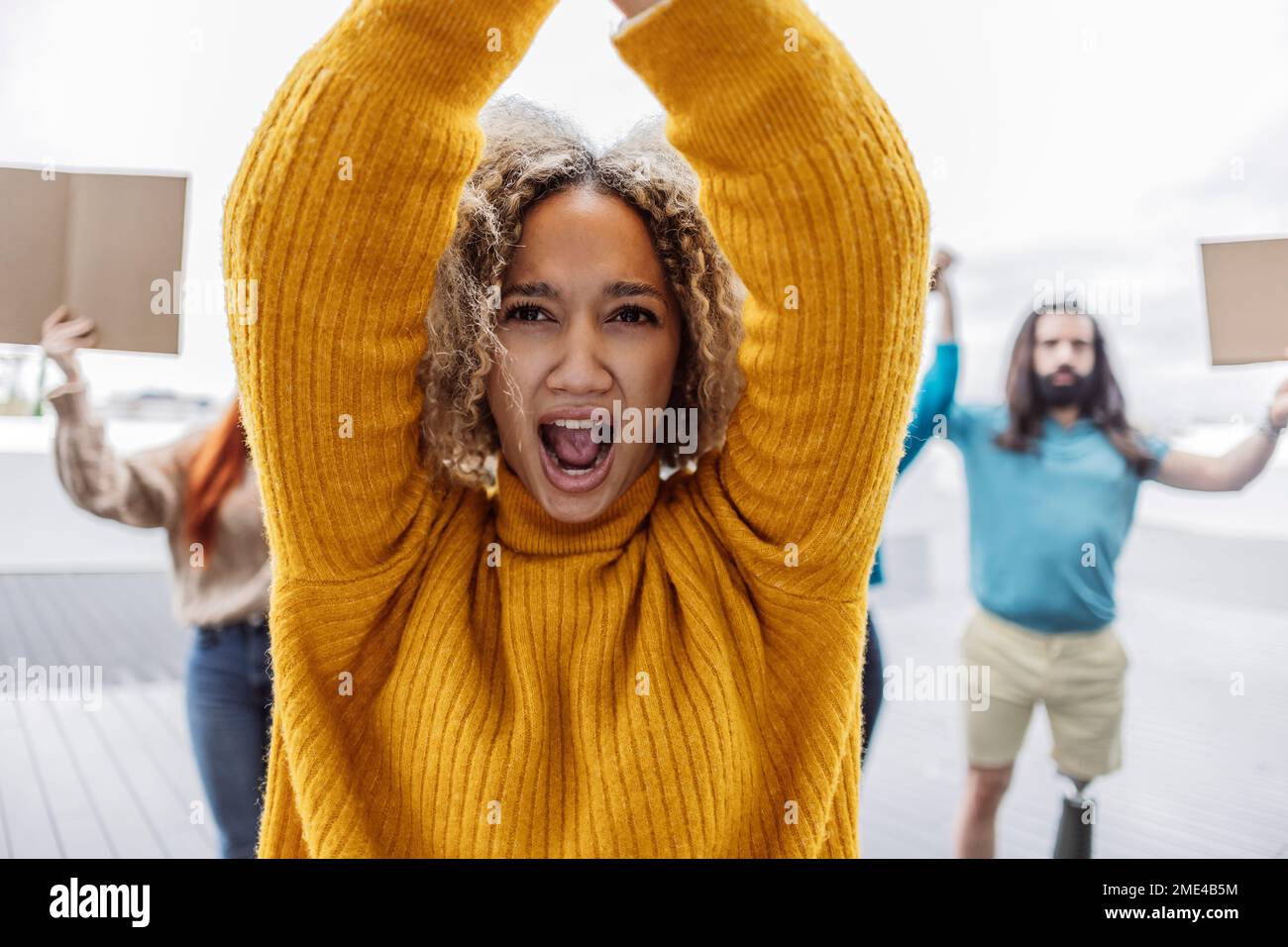 Young woman with arms raised protesting by activists Stock Photo