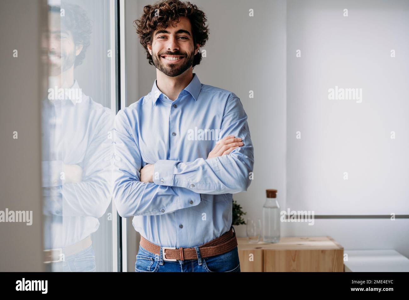 Happy businessman standing with arms crossed in office Stock Photo - Alamy