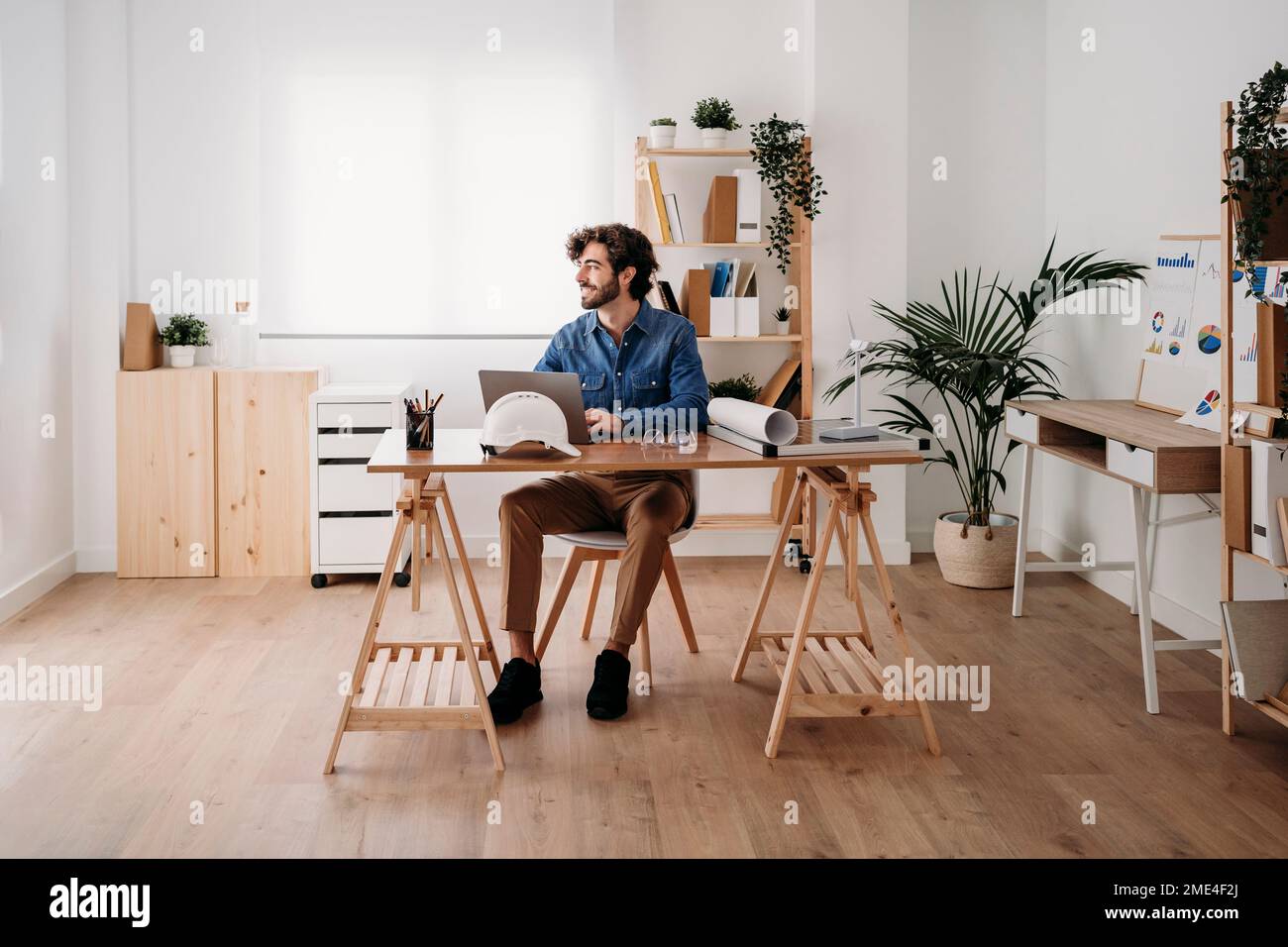 Smiling engineer working on desk with laptop in office Stock Photo
