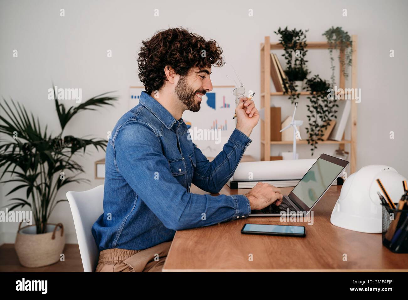 Smiling young engineer working on laptop in office Stock Photo