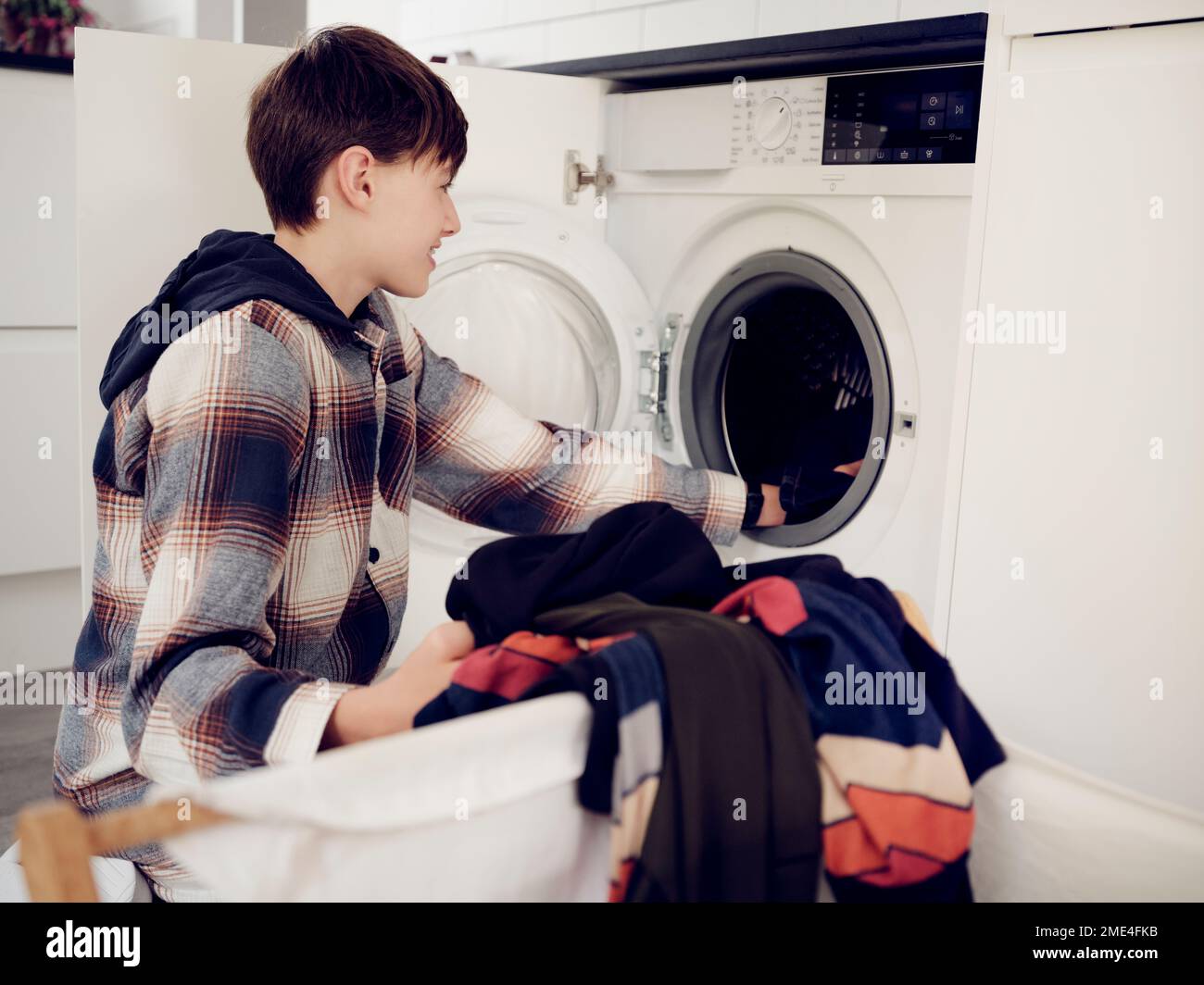 Boy putting laundry into washing machine at home Stock Photo Alamy