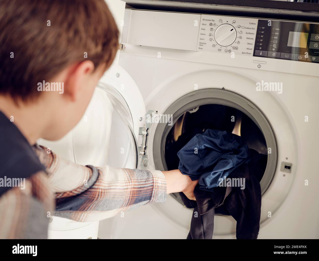 Boy putting laundry into washing machine at home Stock Photo Alamy