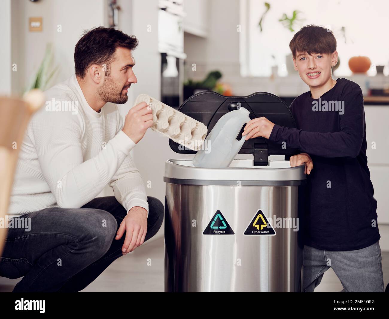 Father and son sorting waste paper and plastic into a sorting bin Stock Photo