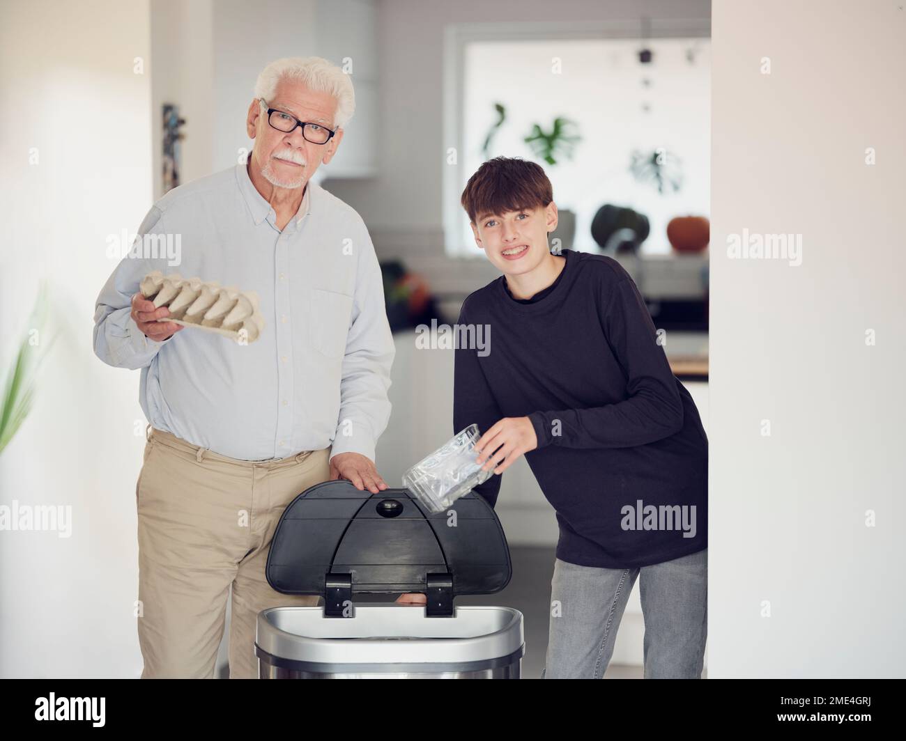 Grandfather and grandson sorting waste paper and plastic into a sorting bin Stock Photo