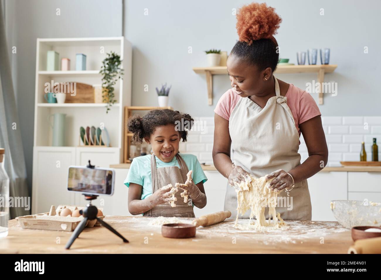 https://c8.alamy.com/comp/2ME4N01/portrait-of-happy-black-mother-and-daughter-baking-together-in-home-kitchen-with-smartphone-camera-recording-video-copy-space-2ME4N01.jpg