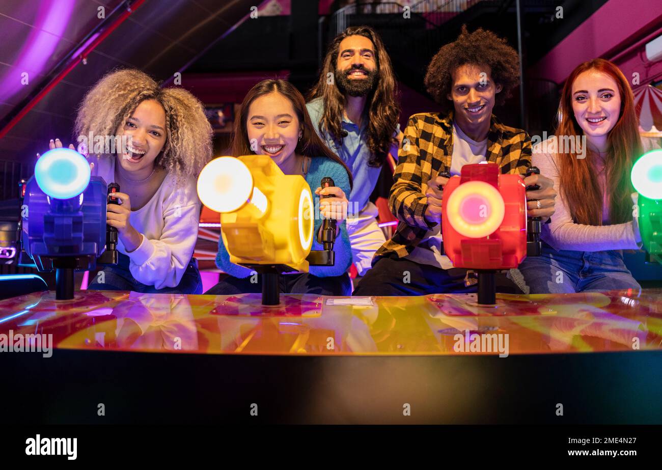 Multiracial friends playing video game in amusement arcade Stock Photo ...