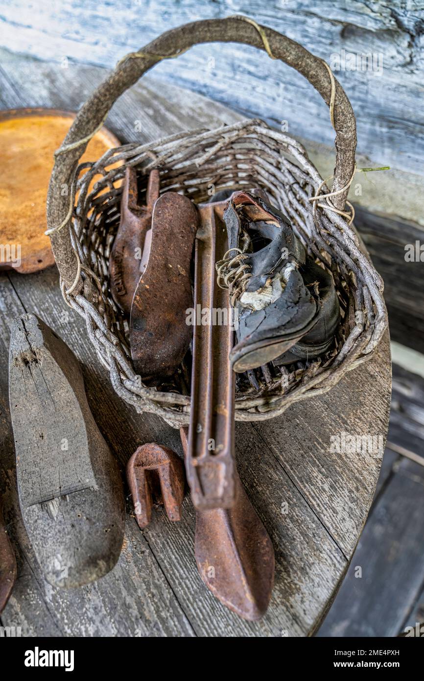 A basket of shoes and shoe making tools outside a pioneer cabin at the