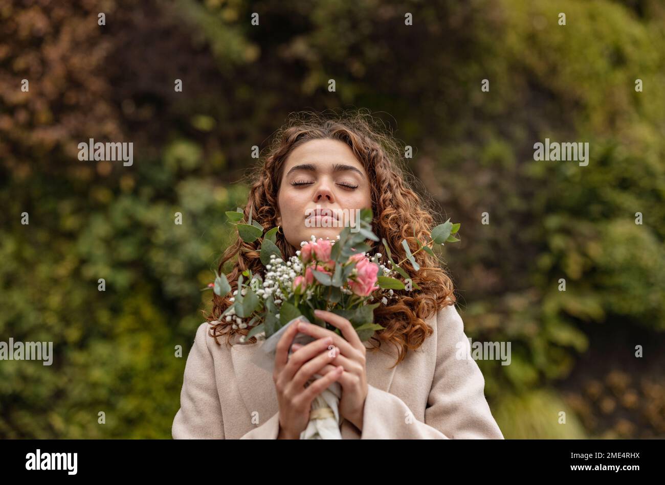 Young woman with eyes closed holding bouquet of flowers Stock Photo - Alamy