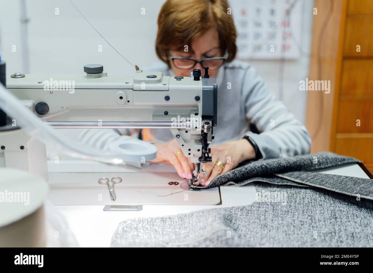 Senior craftswoman using sewing machine in workshop Stock Photo
