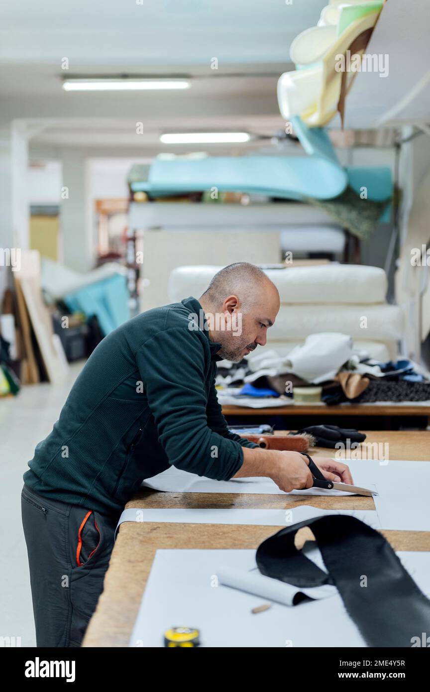 Upholsterer worker cutting fabric at workbench Stock Photo Alamy