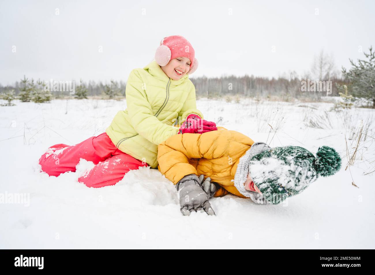 Happy girl playing and having fun with brother in snow Stock Photo - Alamy