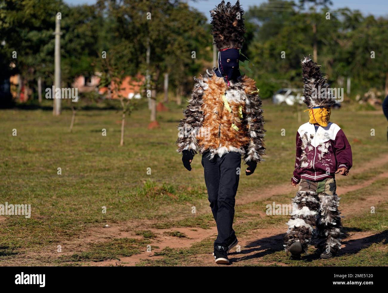 Catholic parishioners Kevin Candia, 15, left, and Lucas Gonzalez, 8, walk  to church wearing their feathered costumes during the feast day of St.  Francis Solano, in Emboscada, Paraguay, Saturday, July 24, 2021.