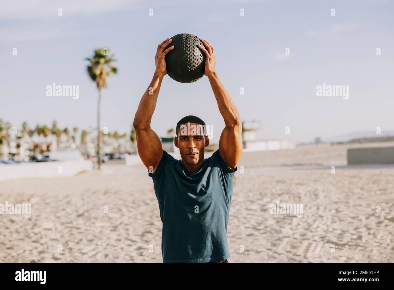 Male athlete exercising with ball on sunny day Stock Photo