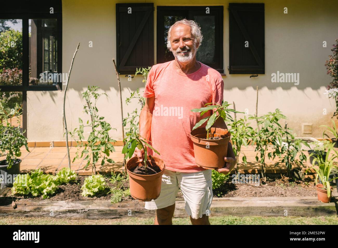 Happy senior man holding potted plant outside house Stock Photo - Alamy