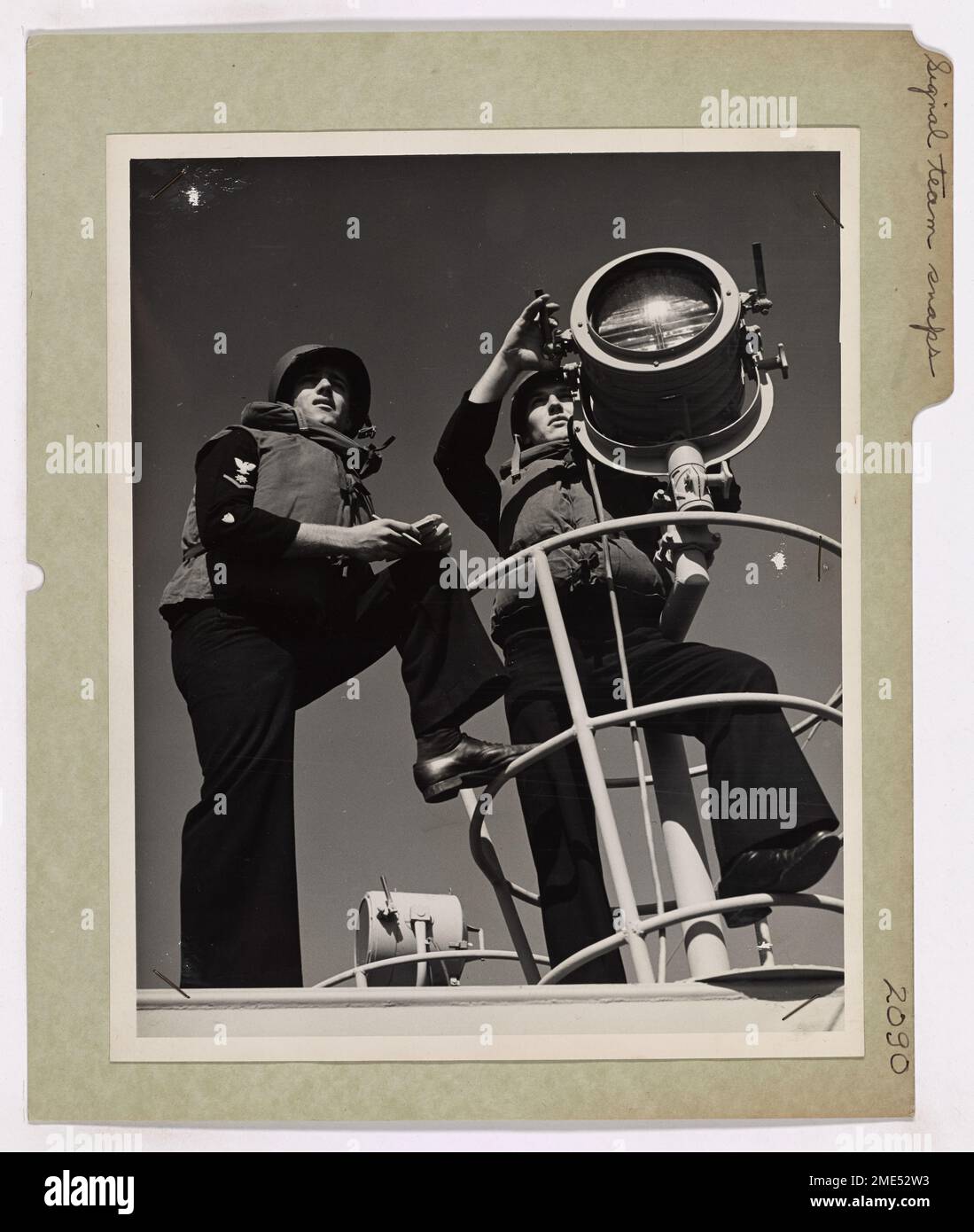 Coast Guardsmen Act as Recorder and Signalman in This Action Shot Aboard a Coast Guard-manned Landing Ship. Signal Team Snaps Into it on LST Unit. Coast Guardsmen C. W. Haaren, left, Q.M.3c of New York City and Corte Severino, S.M.3c, of Chicago, act as recorder and signalman in this action shot aboard a Coast Guard-manned LST (Landing Ship, Tanks). These men are expert operators of the vital blinker communications system employed by the Coast Guard on all sea-going units. Stock Photo