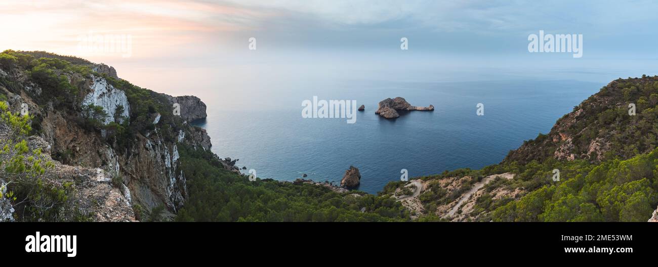 Spain, Balearic Islands, Panoramic view of Ses Margalides rock arch and surrounding sea at sunset seen from coastal clifftop Stock Photo