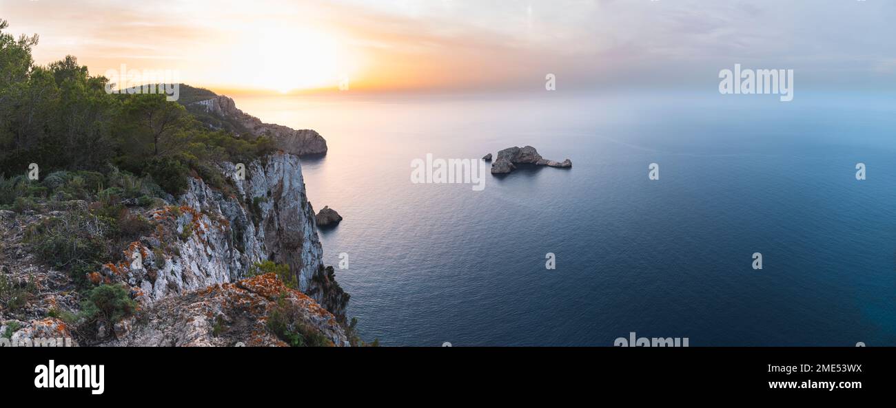 Spain, Balearic Islands, Panoramic view of Ses Margalides rock arch and surrounding sea at sunset seen from coastal clifftop Stock Photo