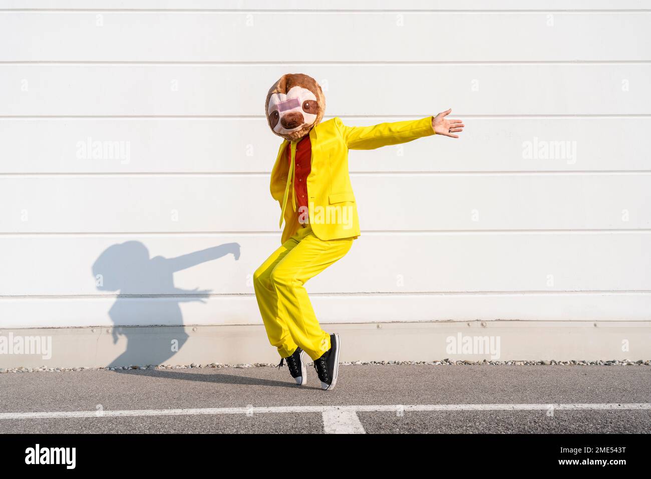 Playful man wearing animal mask dancing in front of wall Stock Photo