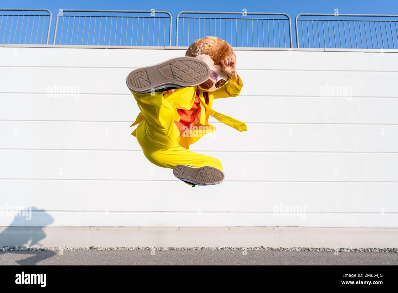 Man wearing animal mask kicking and jumping in front of wall Stock Photo
